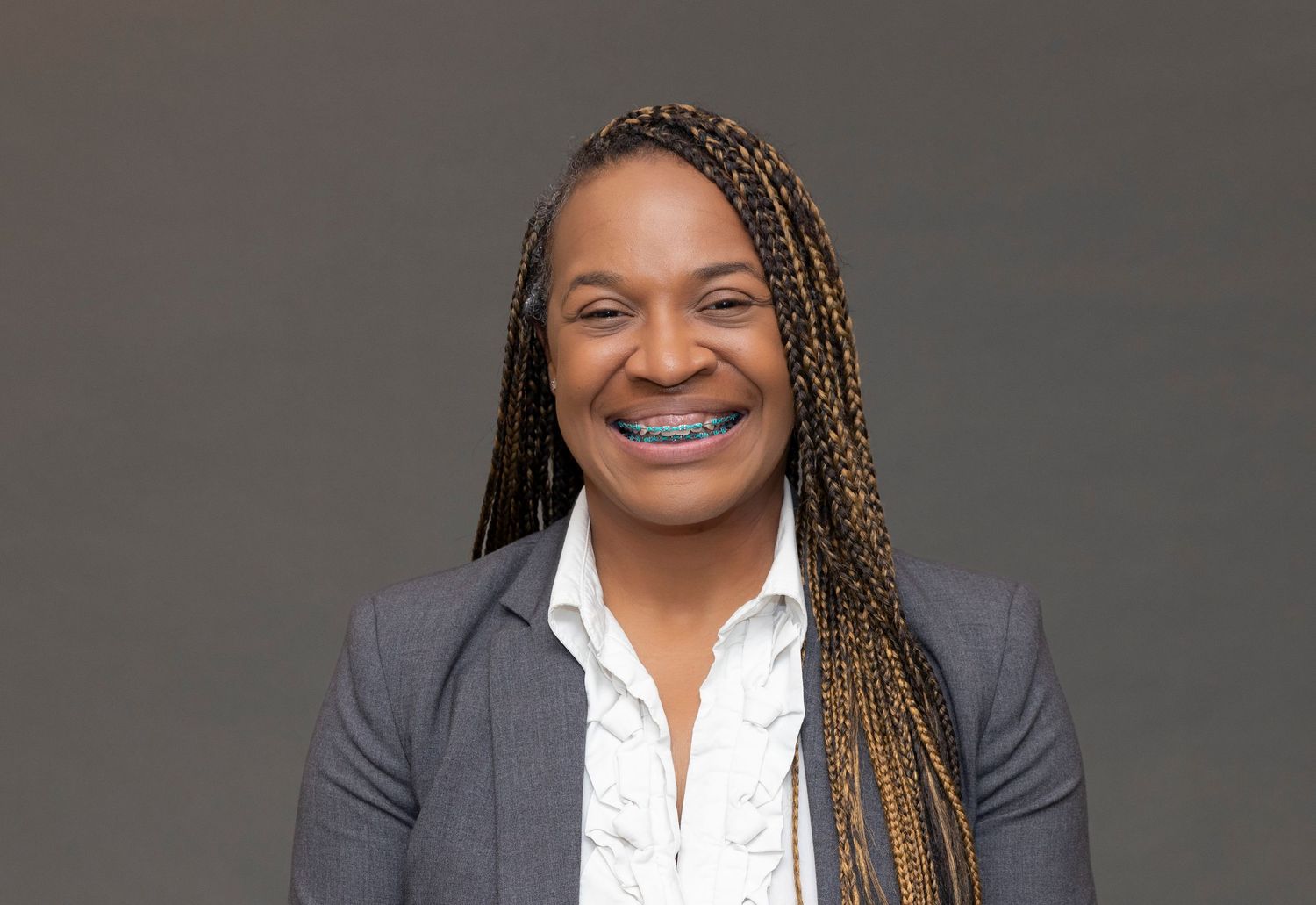 Professional headshot of a person with braided hair wearing a white button-down shirt.