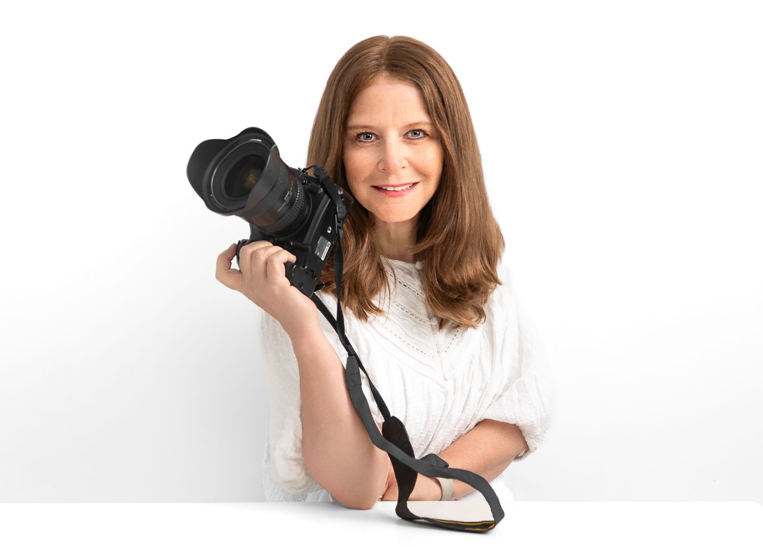 Flora Levin Photographer with brown hair smiling and posing against white background in casual white shirt.
