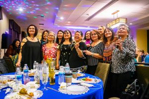 Party celebration in a hall with blue lighting and decorated tables.