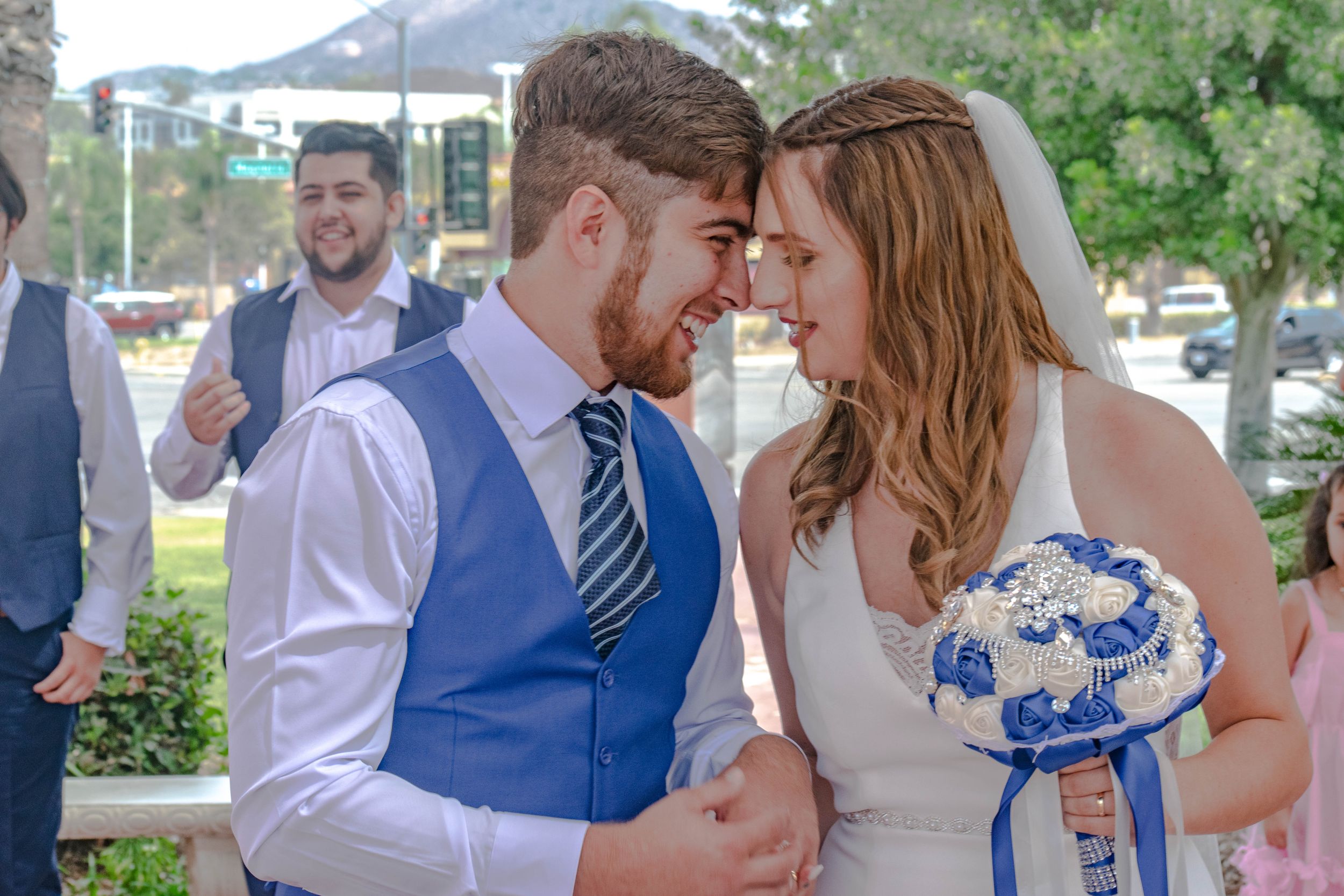 Wedding party celebrates with hugs and smiles in an outdoor garden setting.