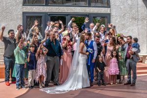 Large group of wedding guests gathered outside a building for a celebratory photo.