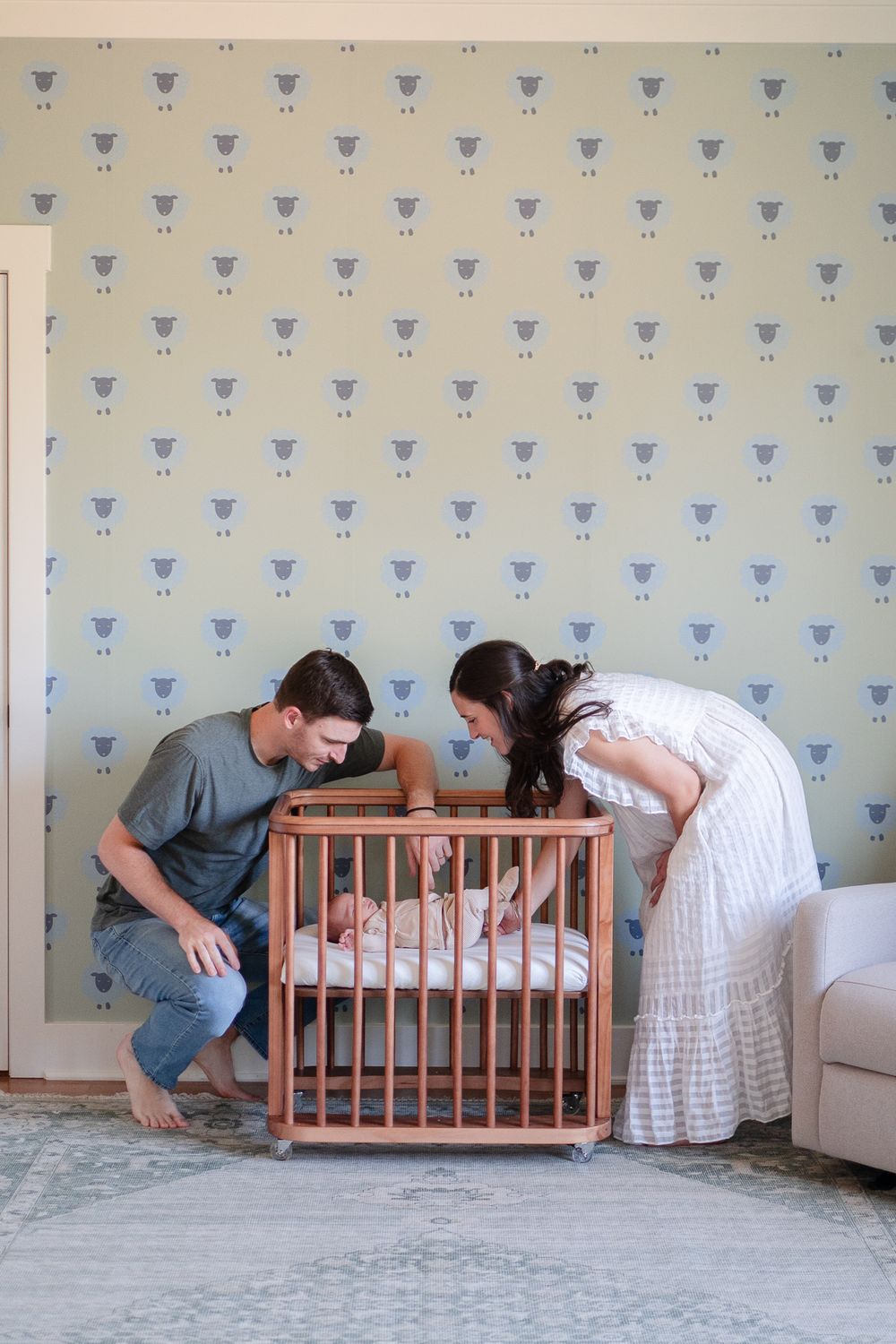 Mom and dad check on baby in his crib during their newborn shoot at home.