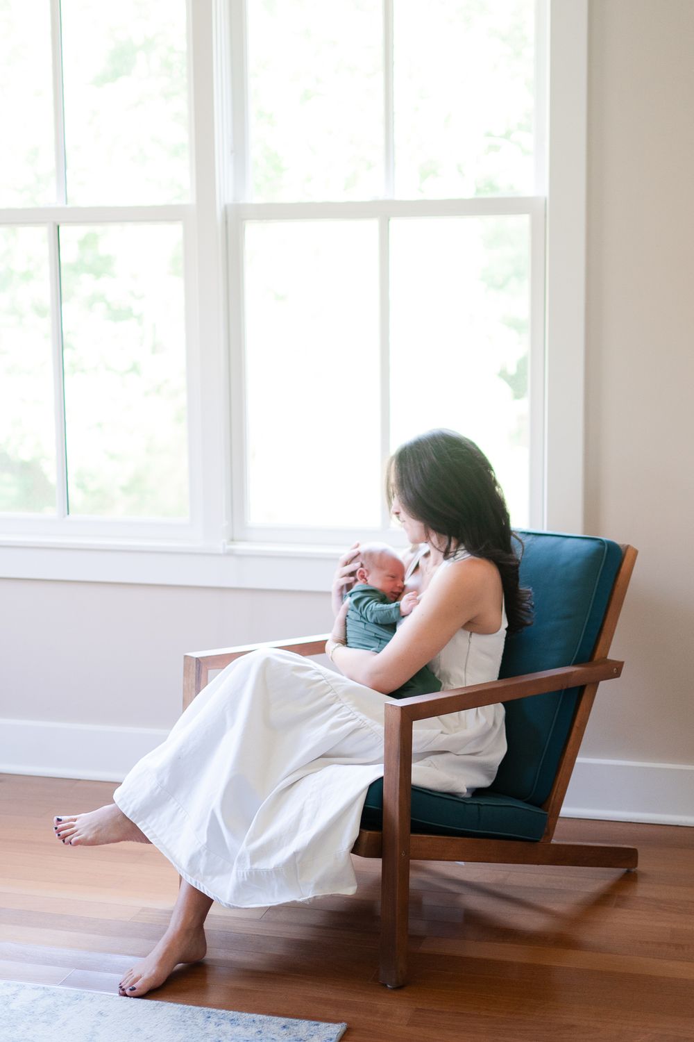 Winston-Salem mom sits in the warmth of their home during the newborn session.