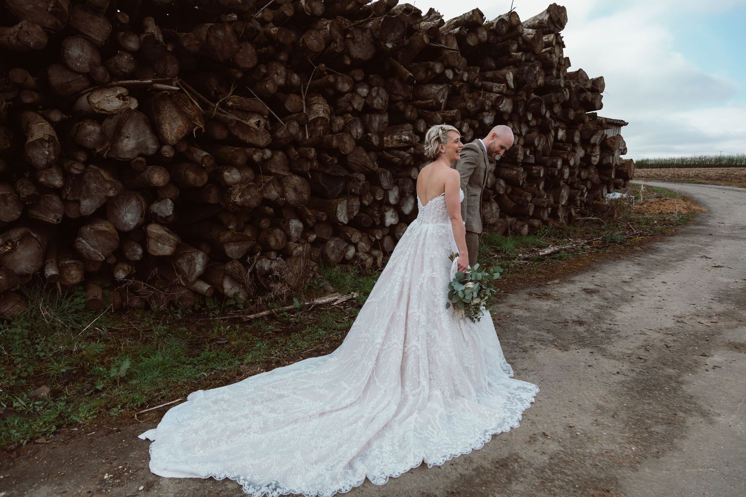 Bride in lace gown poses along rustic stone wall with dramatic train detail. Photographer. Hull. East Yorkshire. Photography