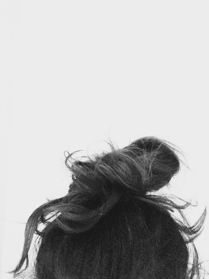 Close-up black and white image of messy hair bun against white background.
