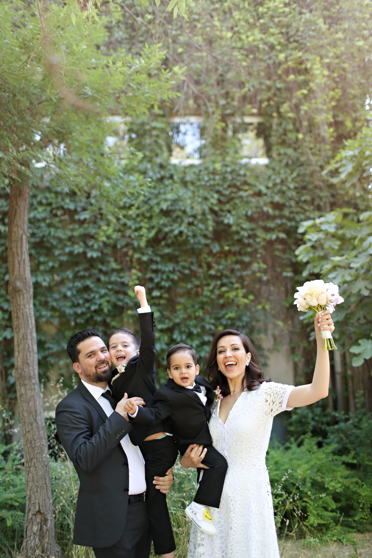 Wedding celebration in garden setting with couple and children sharing joyful moment.