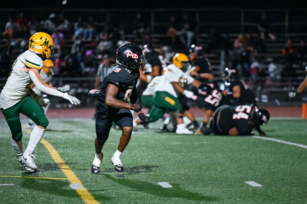Football players from opposing teams face off on the field during gameplay.