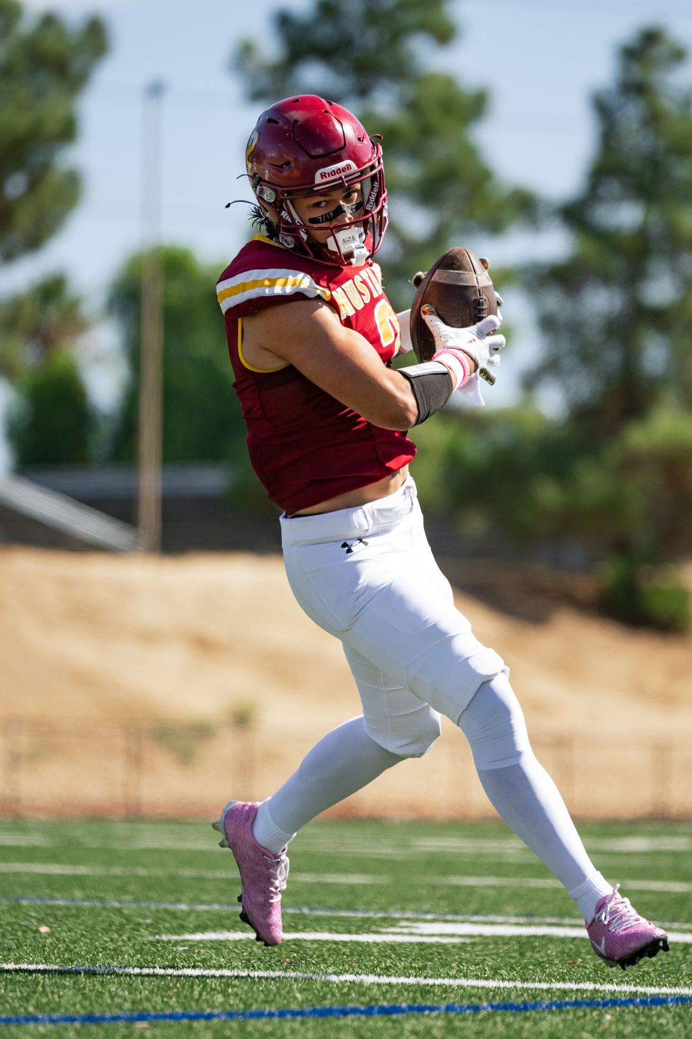 Sequence of athlete in red uniform running across sports field.