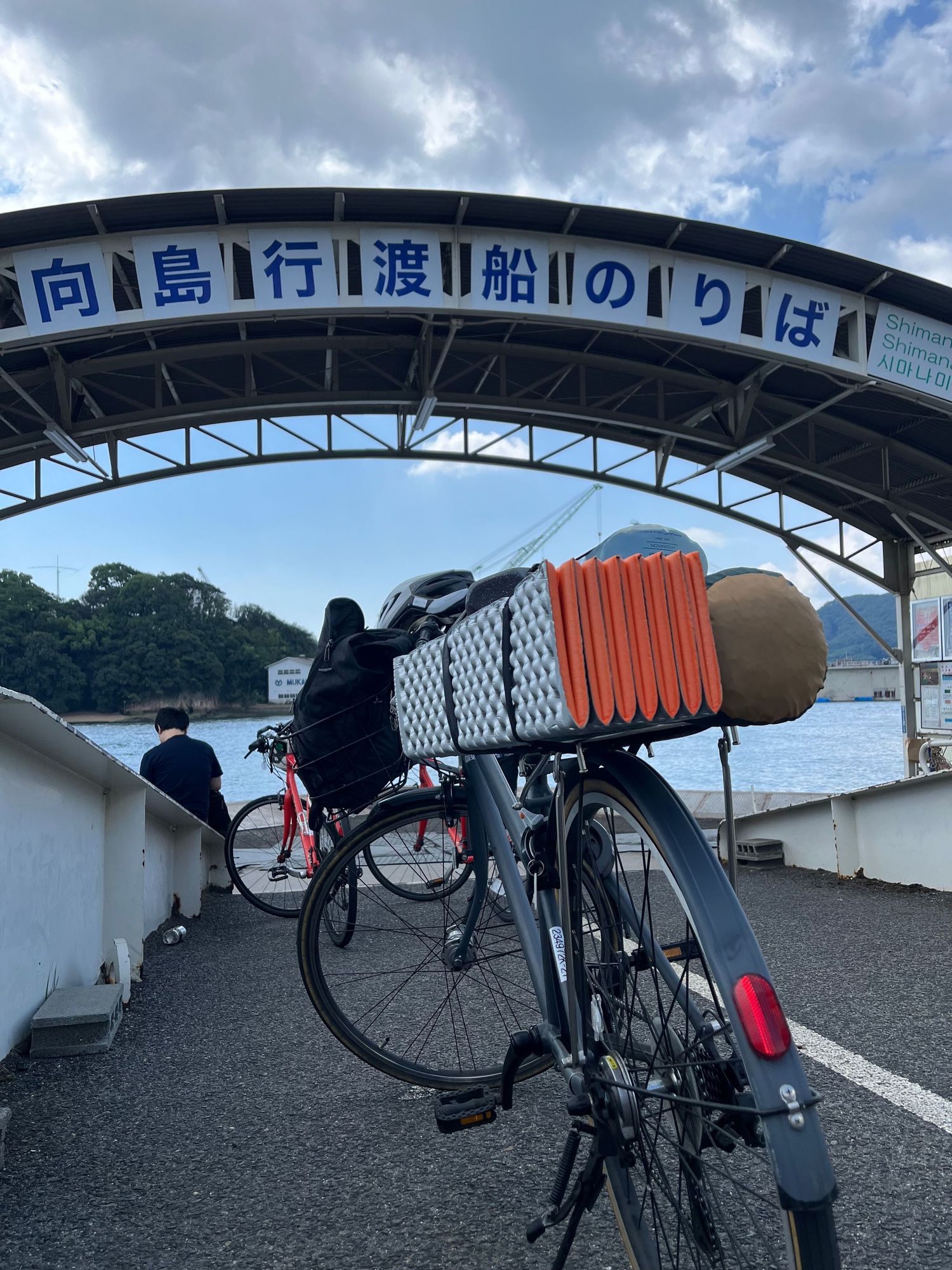 Series of black bicycles parked under a Japanese language sign and archway.