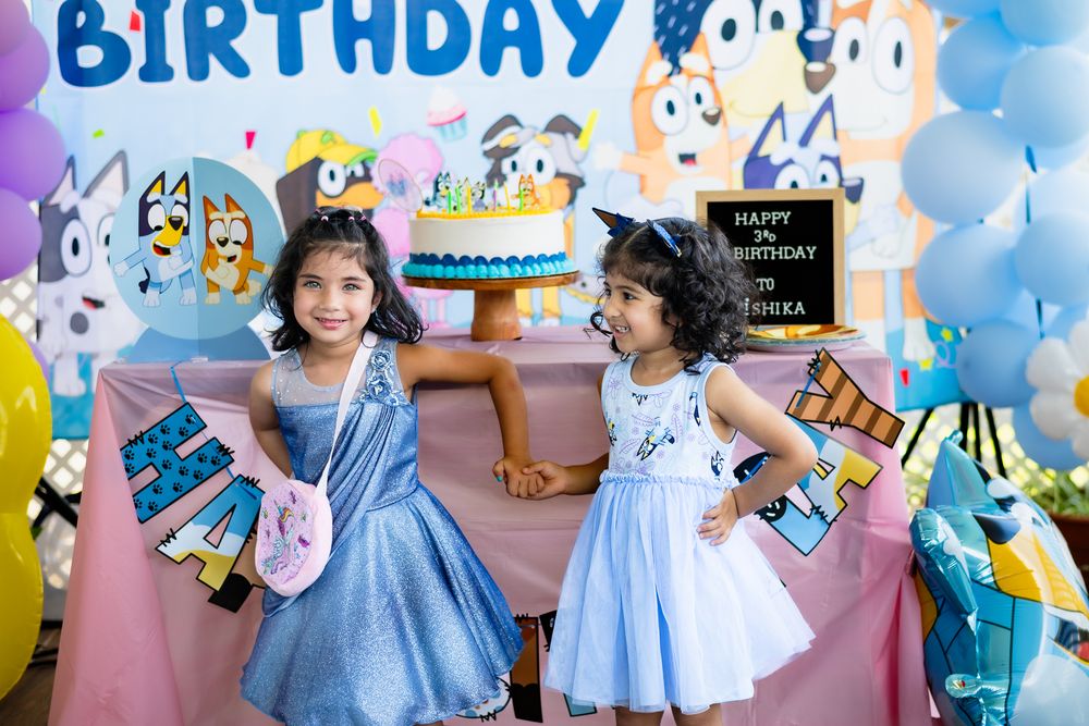 Children in princess dresses at a Bluey themed birthday party with balloons and decorations.