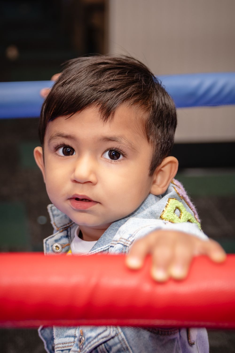 Close up of a young child holding onto a red play structure railing.