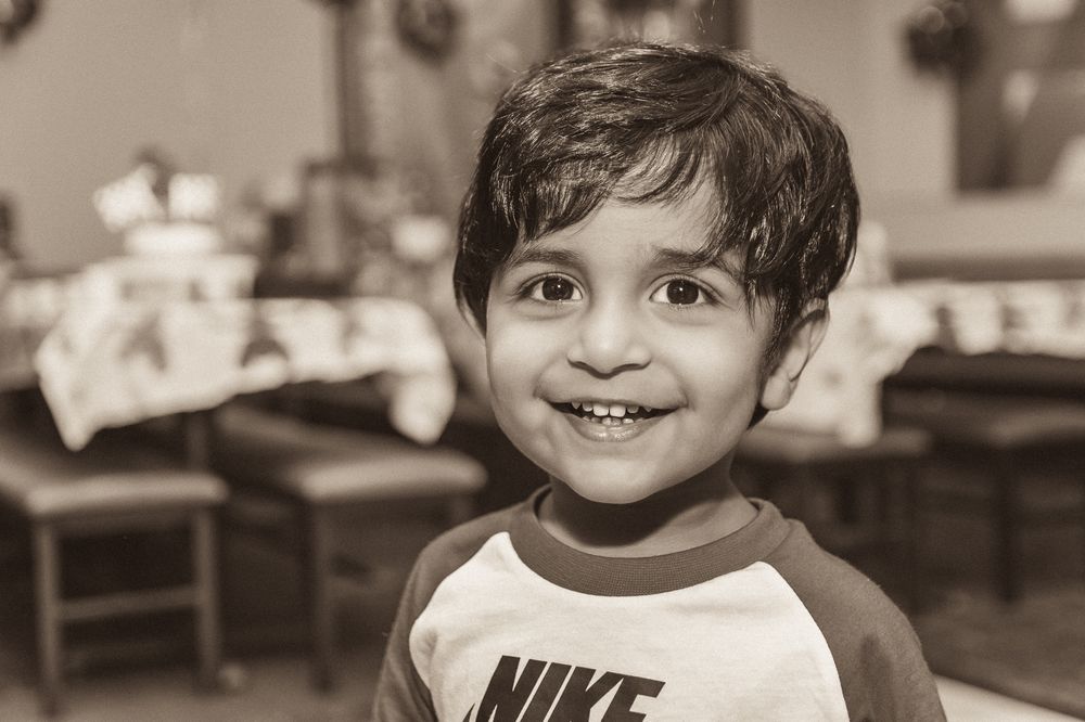 Black and white portrait of a smiling child wearing a Nike shirt.