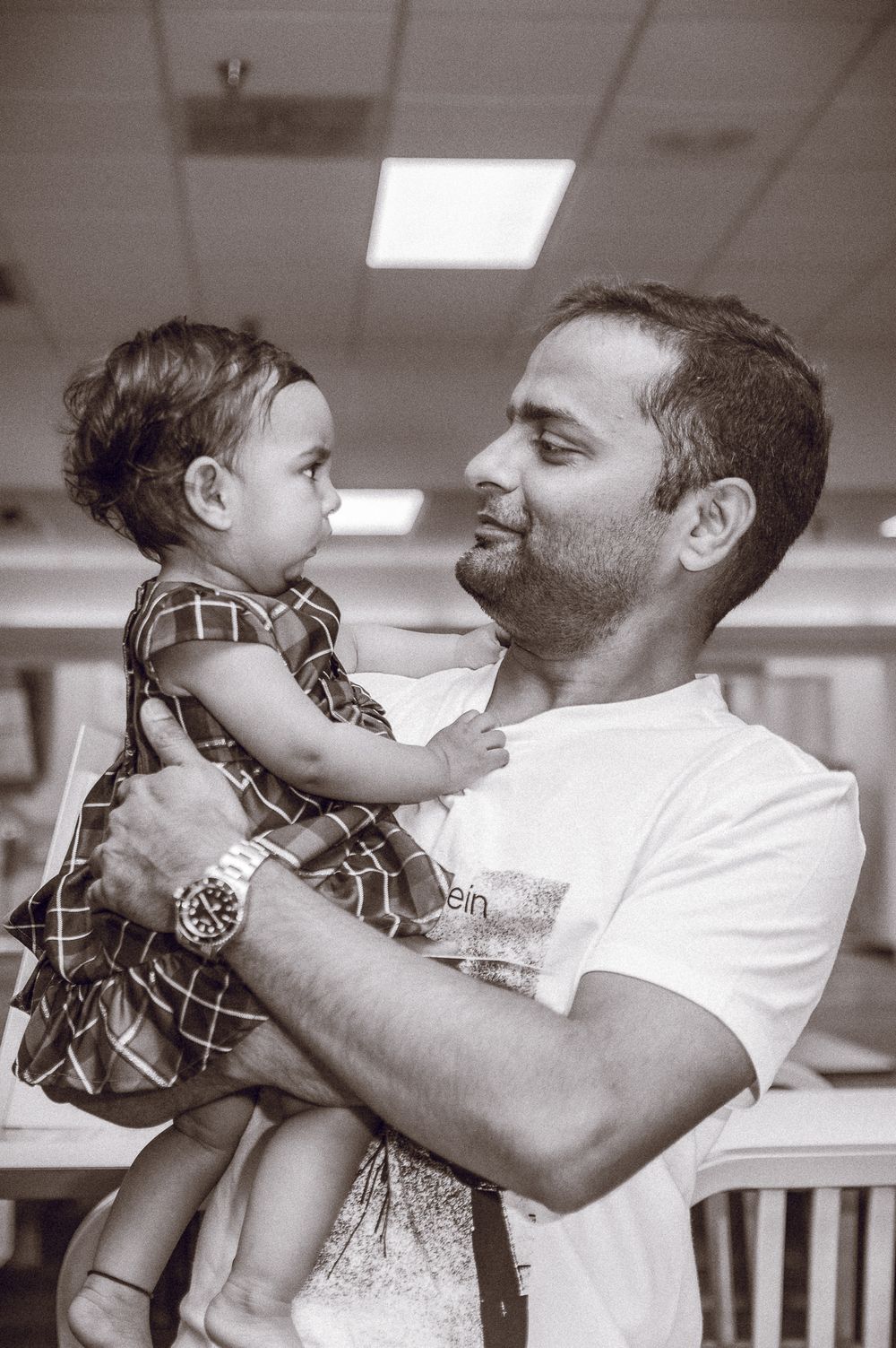 Black and white photo of a tender moment between parent and child indoors.