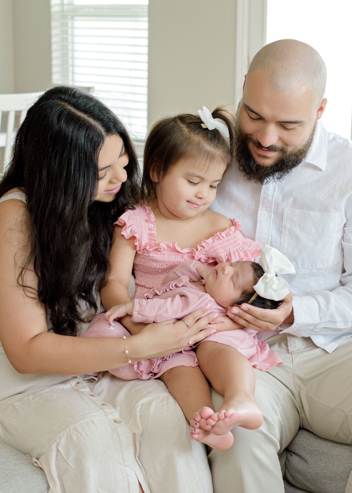 A tender family moment on a couch as they look at their newborn baby.