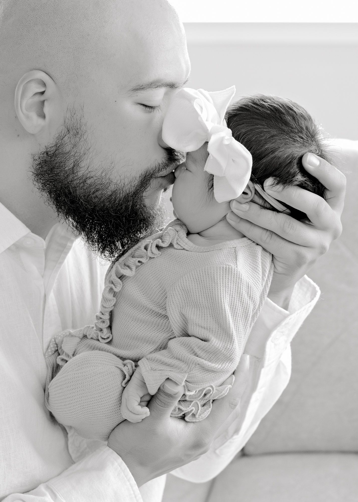 Intimate black and white portrait capturing a tender moment with a baby in ruffled clothing.