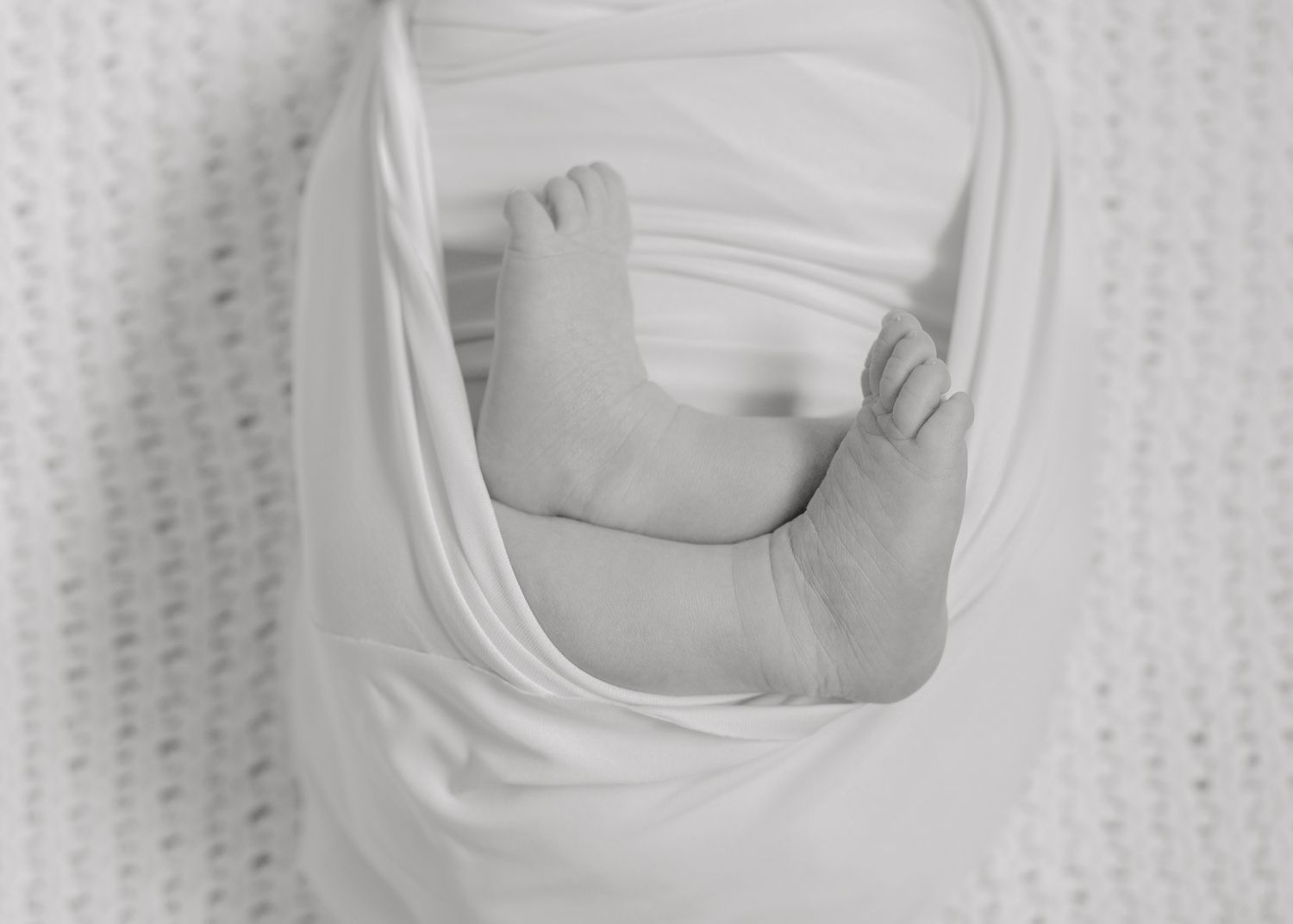 Artistic black and white close-up of baby's tiny feet wrapped up.