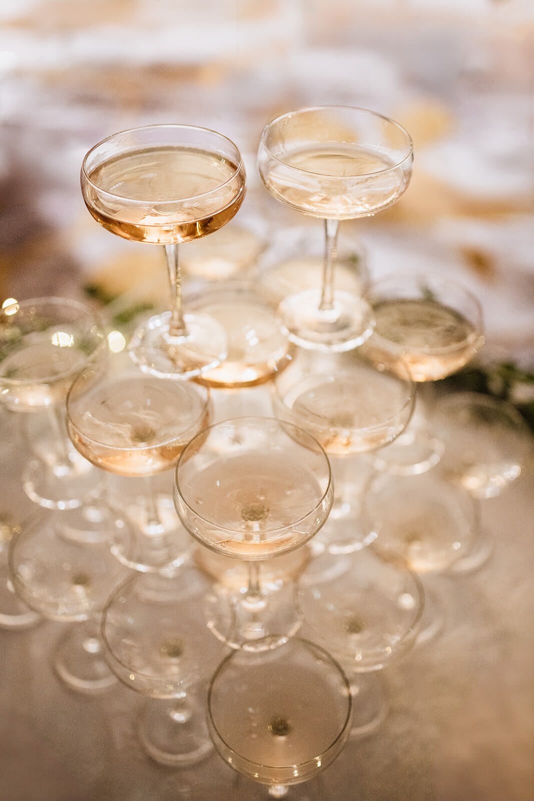 Stacked champagne coupes filled with rose-colored bubbly creating a tower display.
