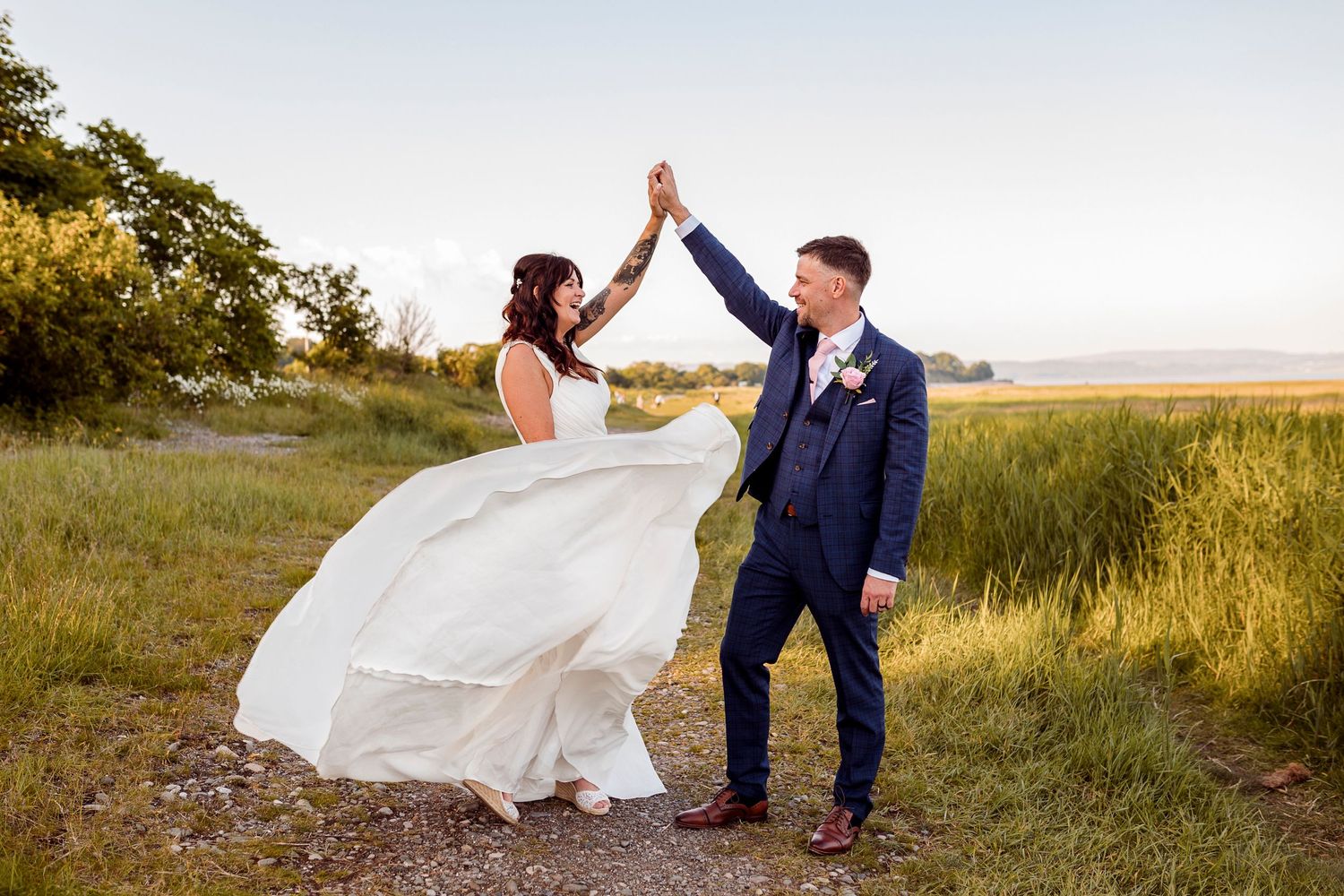 Bride and groom dancing in a field at golden hour with flowing wedding dress.