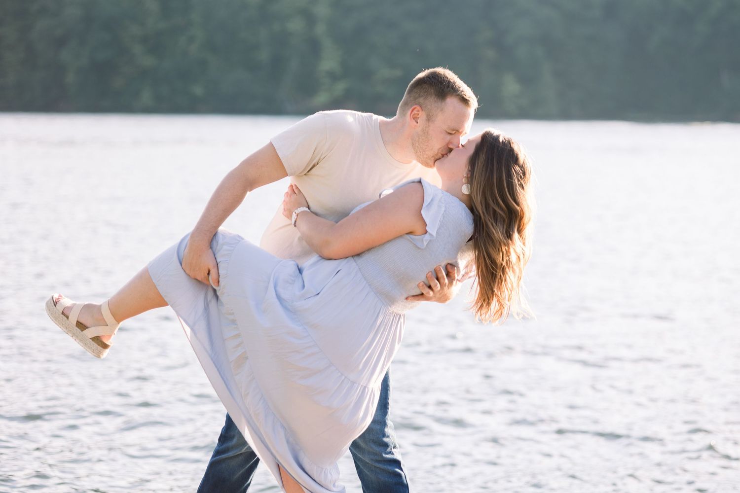 Playful couple shares joyful moments by the water on a summer evening.