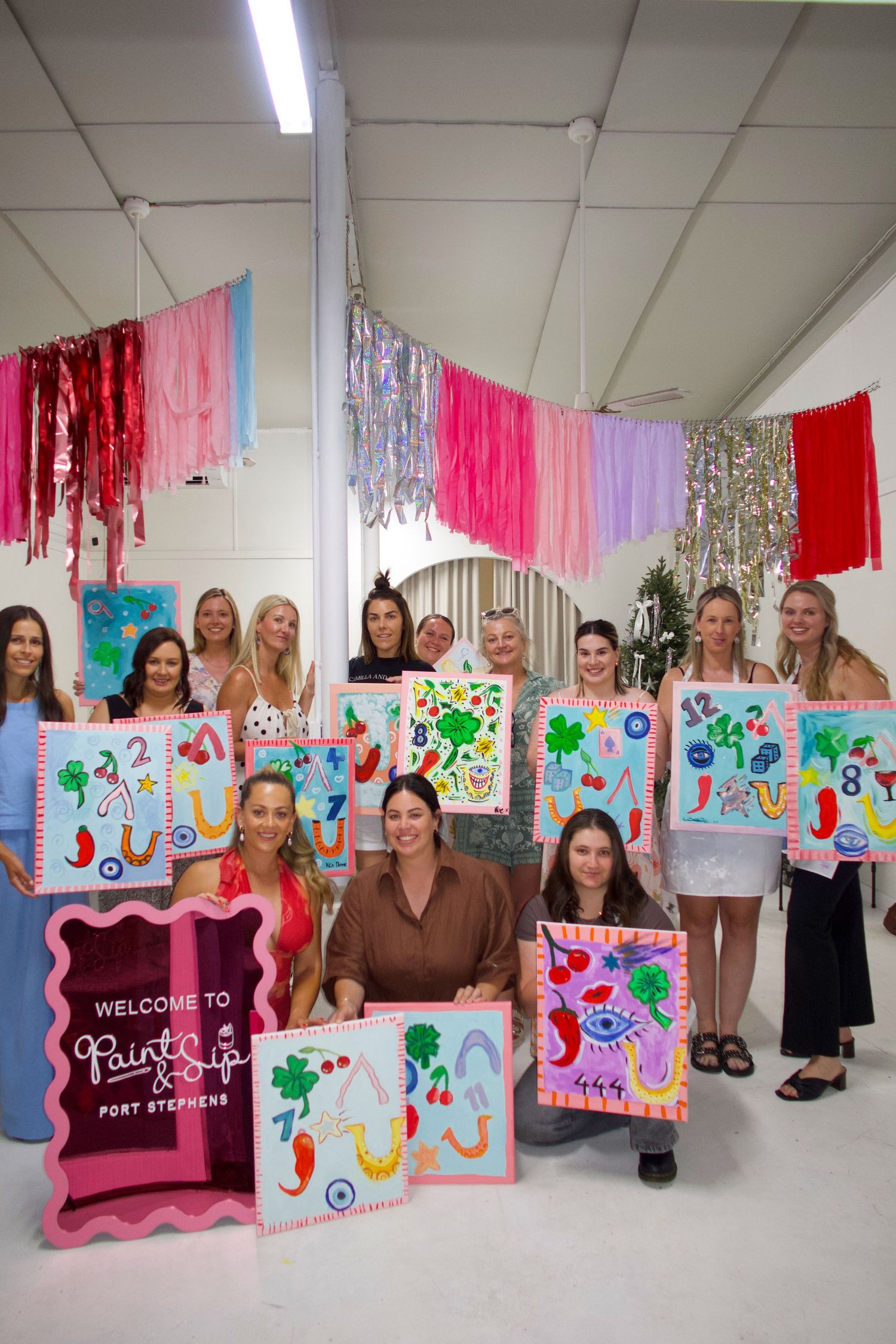 A group paint party with colorful artwork and streamers hanging from the ceiling.