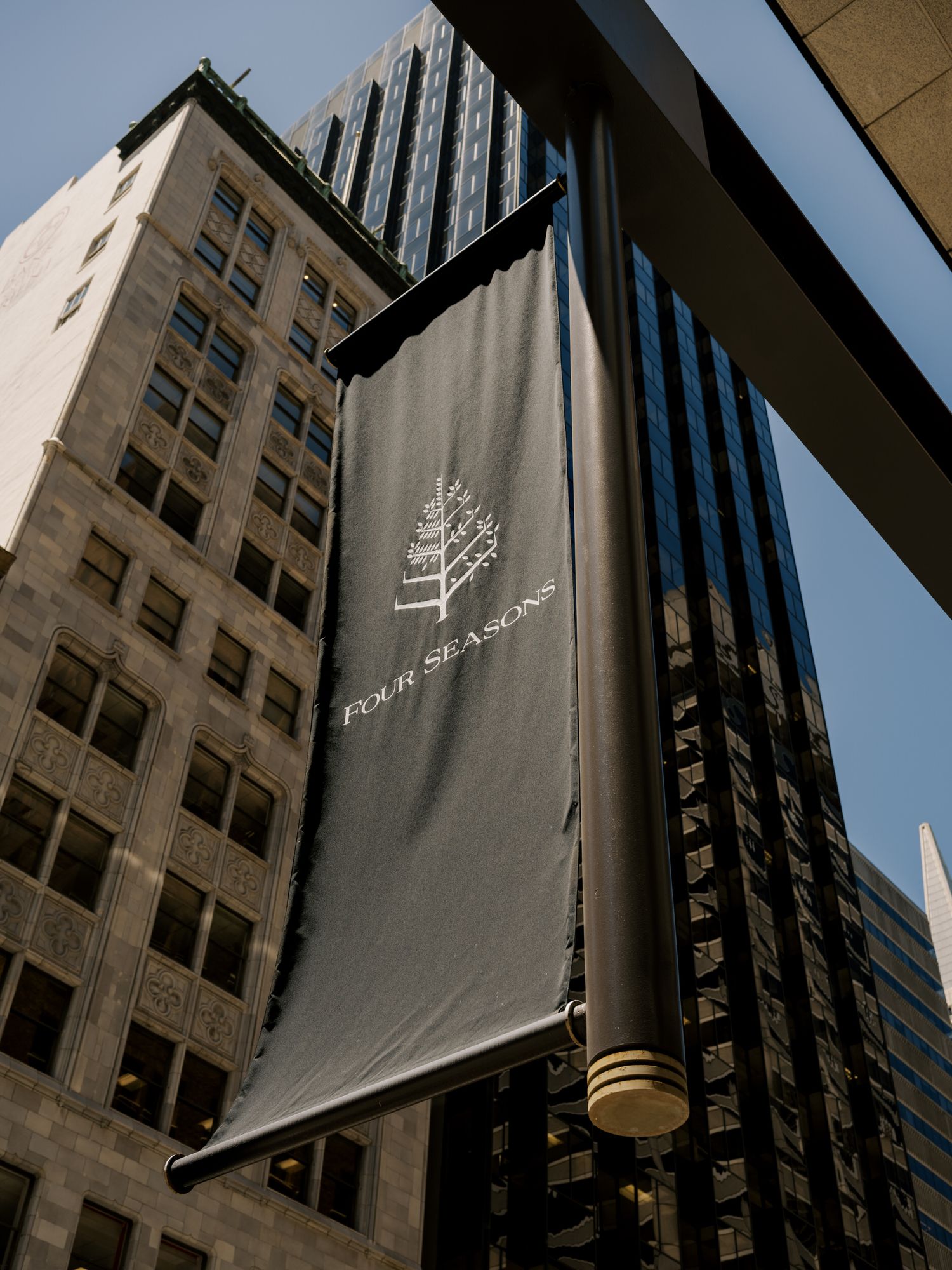 A black banner with the Four Seasons hotel logo hangs outside their hotel property.