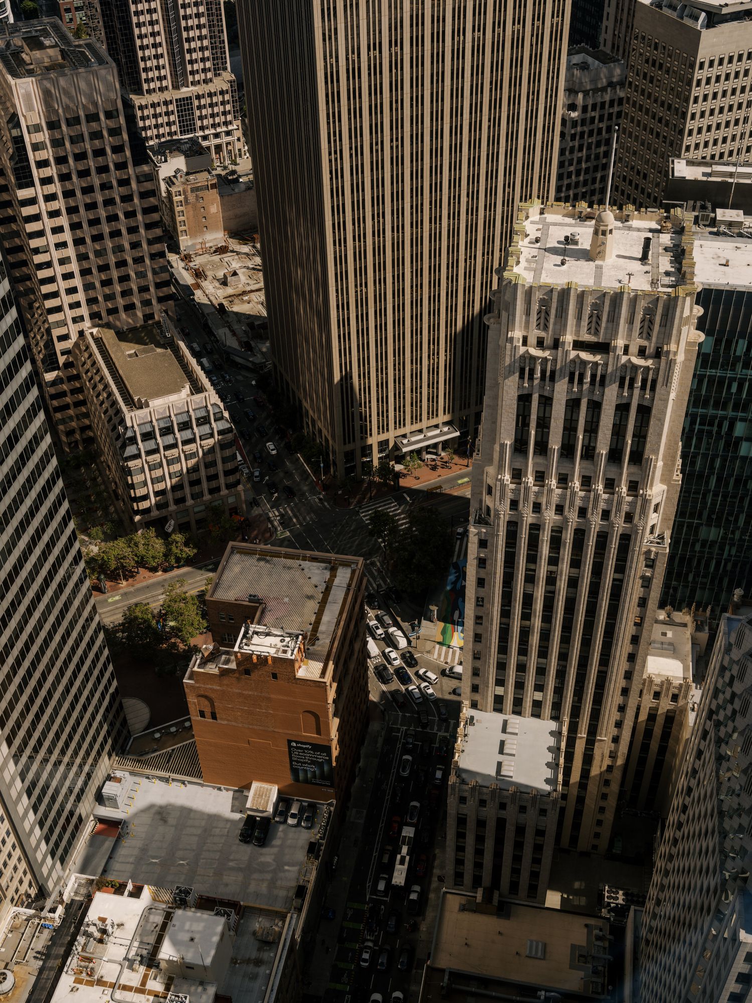 Aerial view of tall skyscrapers and office buildings in an urban San Francisco downtown district with streets below.
