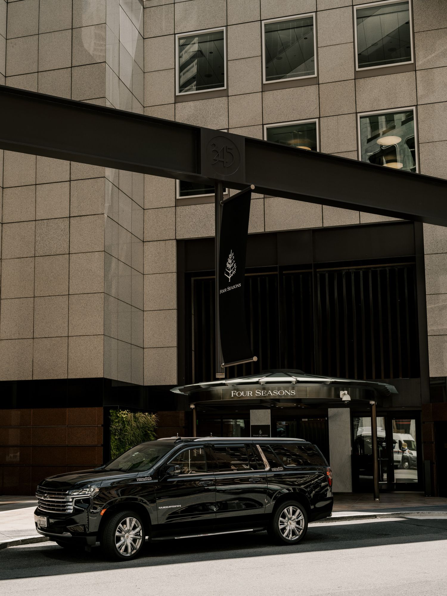 Black luxury SUV parked outside Four Seasons hotel entrance.