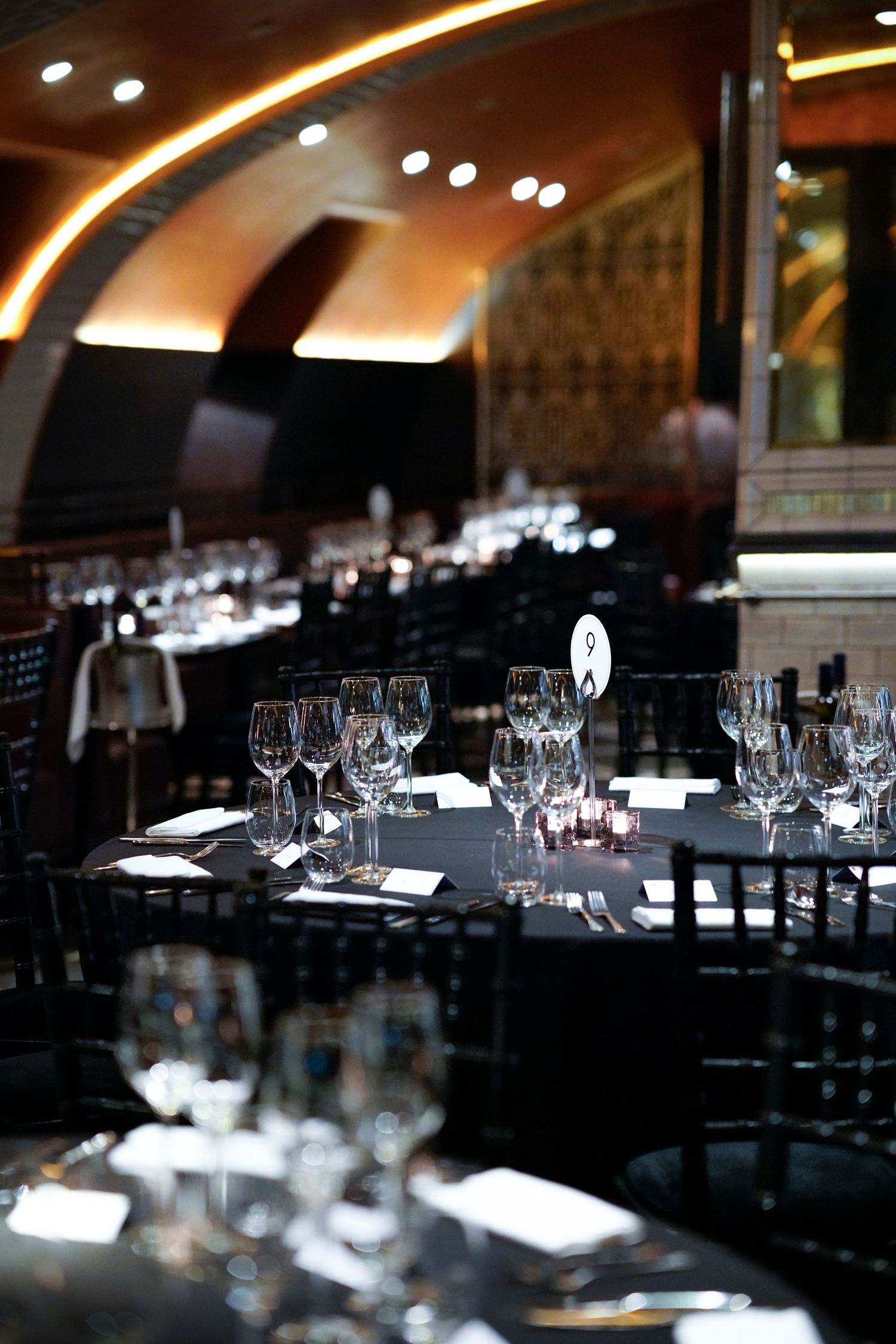 Elegant restaurant interior with curved ceiling and tables set with wine glasses.