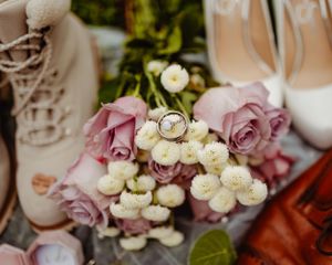 Close-up of wedding rings displayed on delicate white flowers with pink roses.