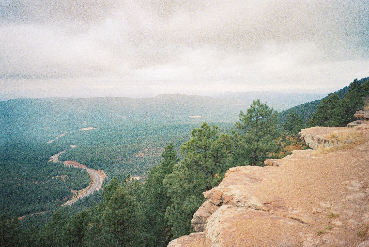Sweeping mountain vista overlooking a vast valley landscape with cloudy skies.