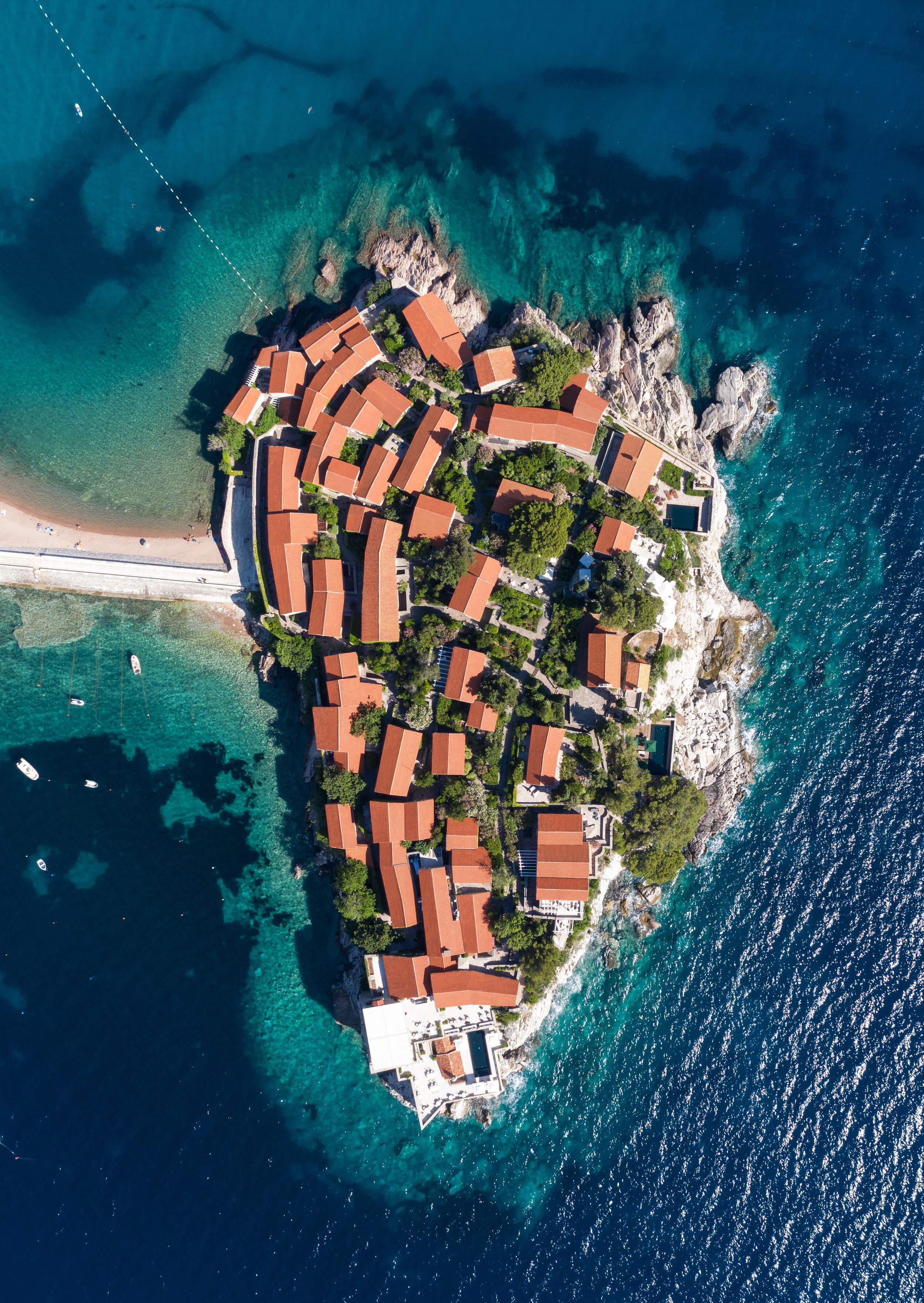Aerial view of a small island village with terracotta roofs surrounded by azure Mediterranean waters.