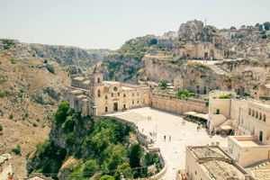 Ancient hillside town with historic buildings and a large square overlooking rugged terrain.