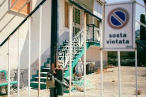 Turquoise metal staircase and no parking sign on a white building exterior.