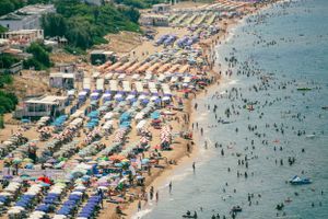 Aerial view of a crowded beach with neat rows of umbrellas and beachgoers along the coastline.