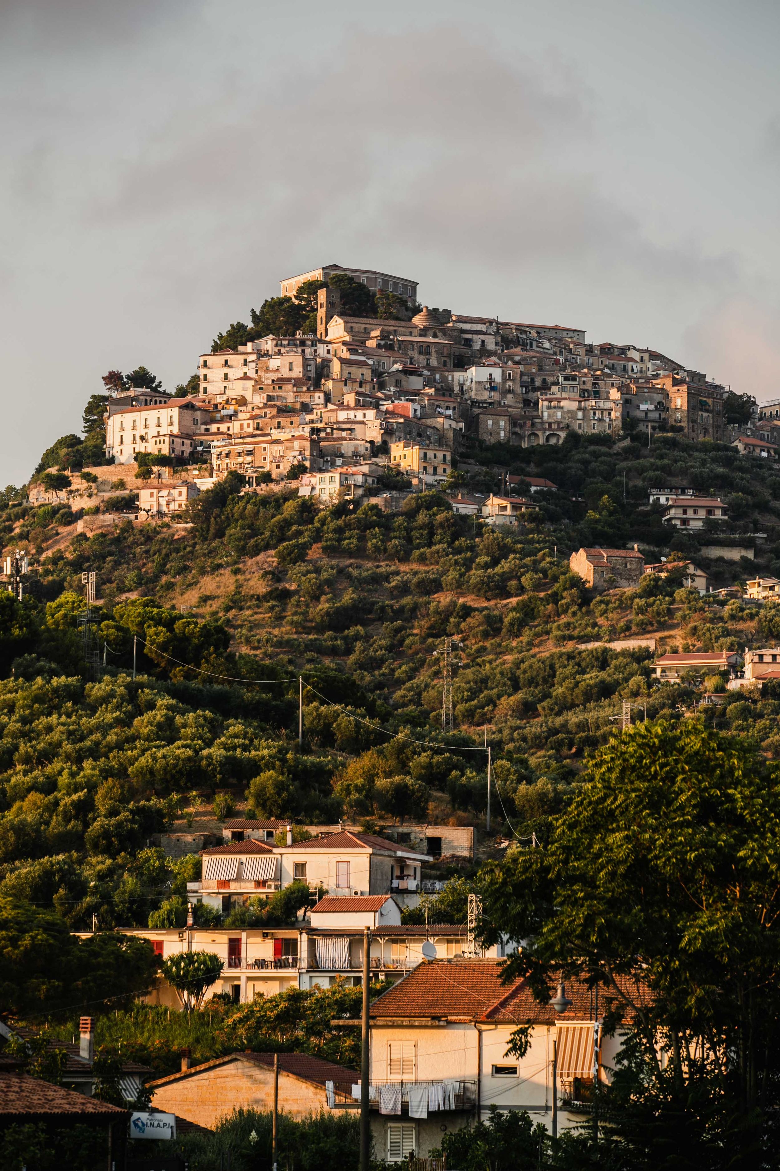 Italian hillside town with clustered buildings cascading down a mountainside at golden hour.