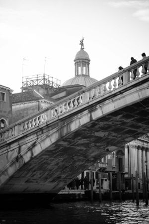 Black and white photograph of historic Venice bridge architecture with domed building in background.
