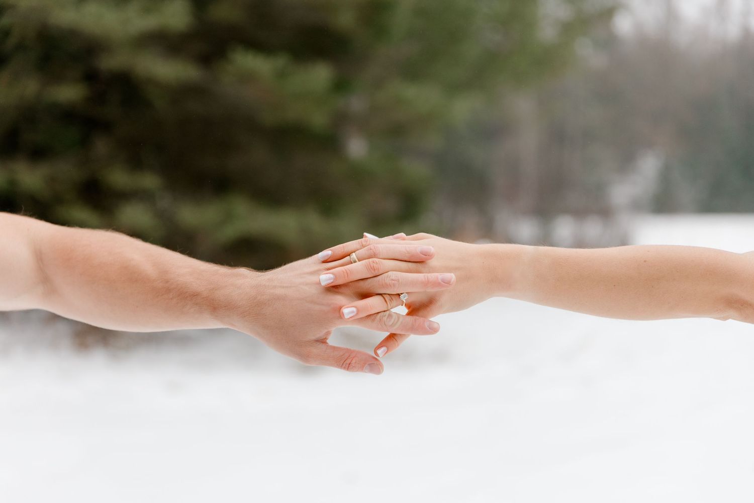 Close-up of couple gently touching hands in snowy winter outdoor setting.