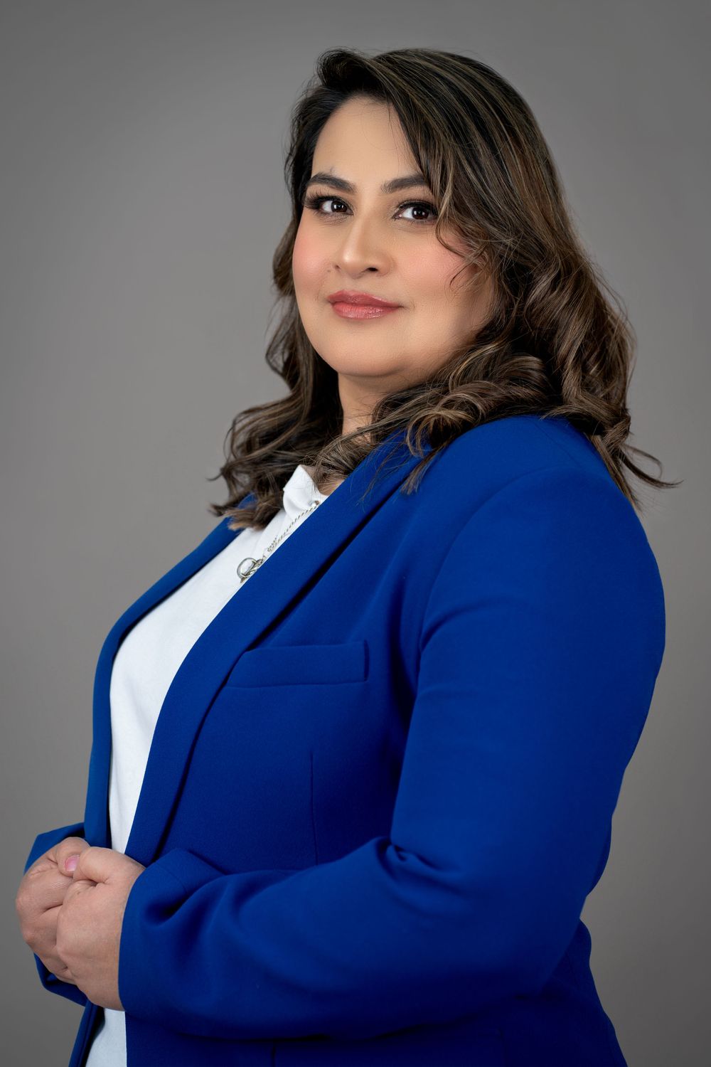 Professional headshots in royal blue blazer and white blouse against gray backdrop.