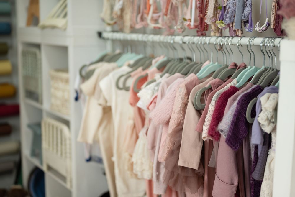 Rows of pastel colored baby clothes hanging neatly on white hangers in a retail store display. Fort Wayne Indiana
