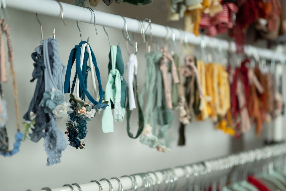 Colorful newborn headbands hanging on display rack arranged by color from blue to pink tones in a photography studio Huntington Indiana