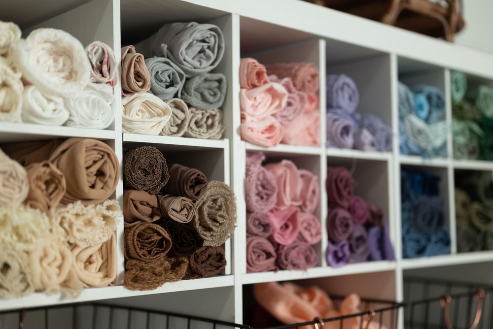 Neatly folded blankets and textiles arranged in white shelving unit displaying various colors from cream to blue. Wabash Indiana