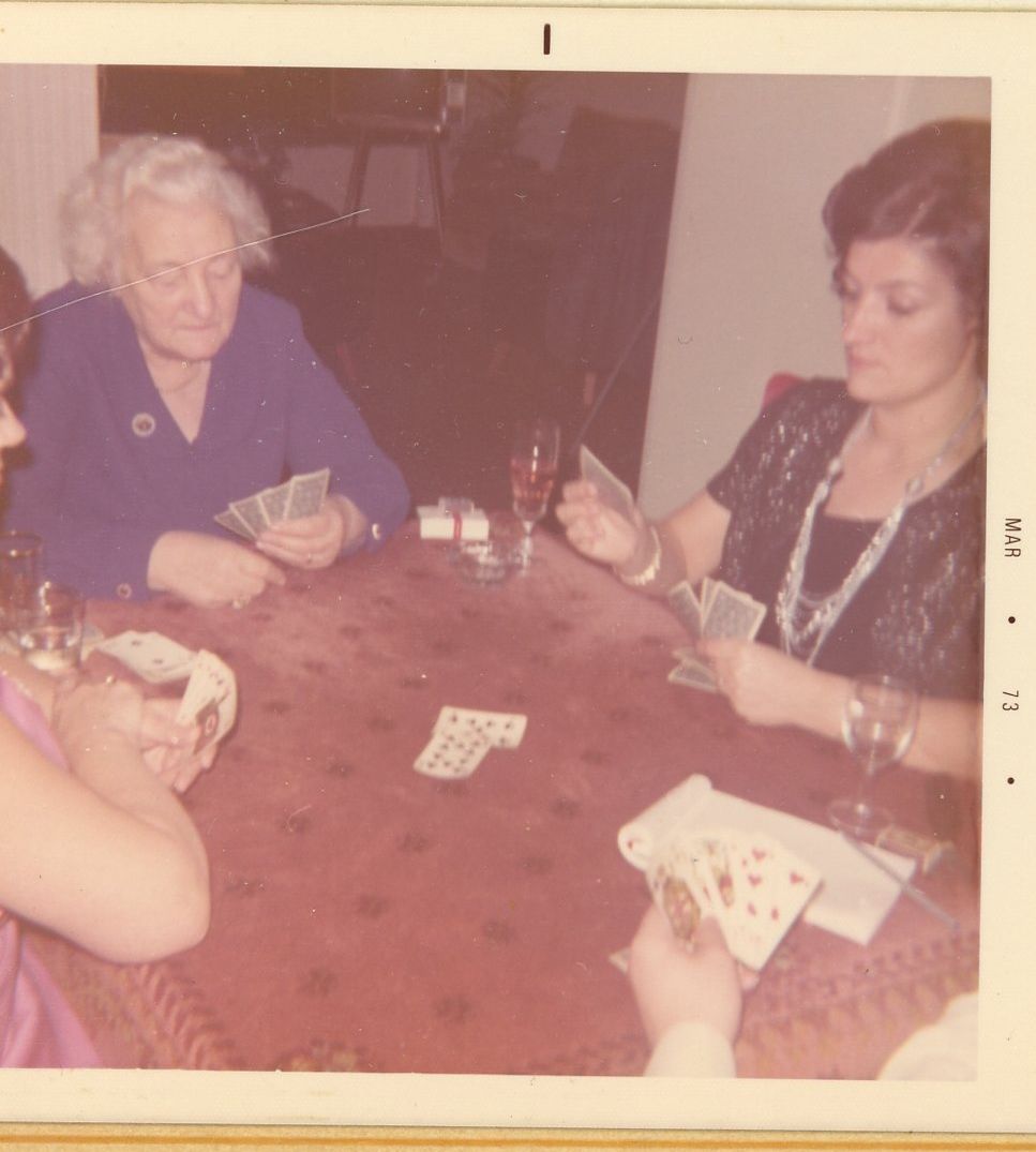 Vintage color photo of people playing cards around a wooden table.