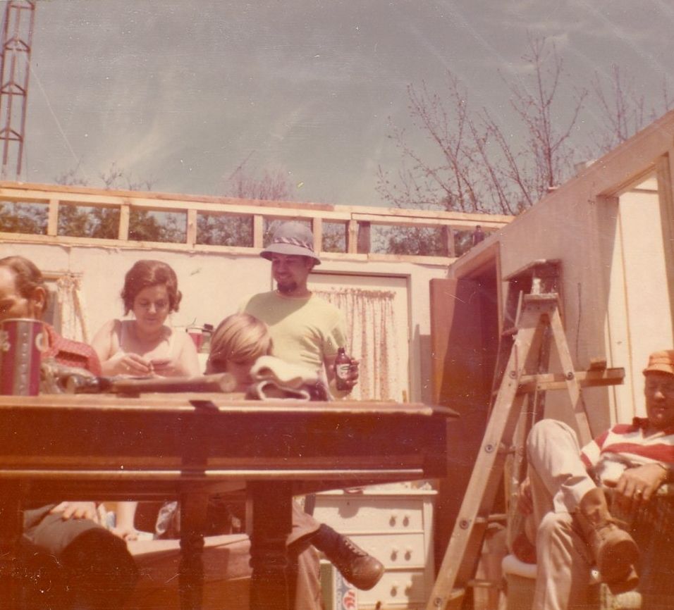 Vintage color photograph of people gathered around an outdoor deck or construction project.