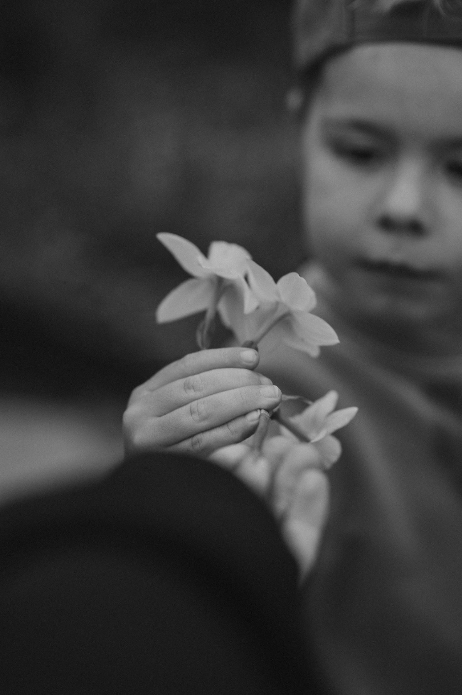Child gently holds delicate white flowers in a black and white photograph.