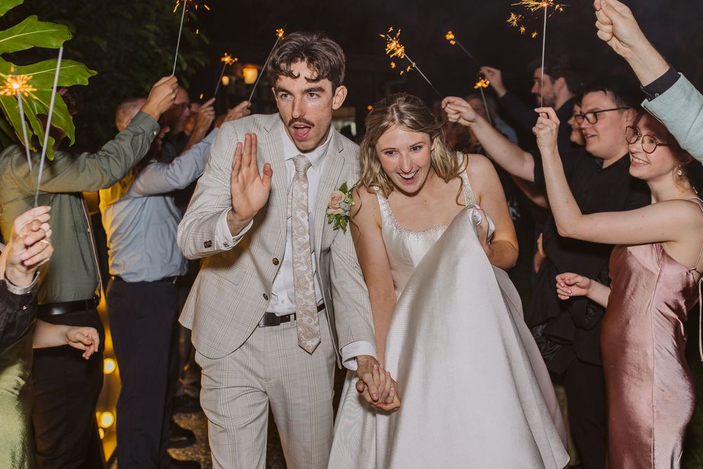 Newlyweds and wedding guests dancing enthusiastically at an outdoor evening reception celebration.
