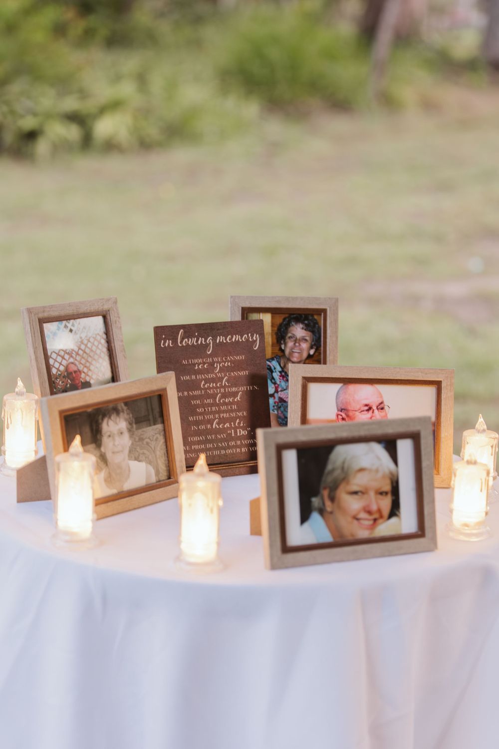 Memorial table with framed photos and glowing candles at wedding reception.