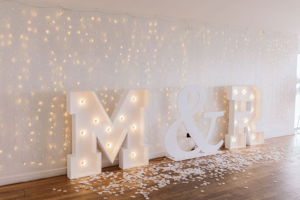 Illuminated paper bag lanterns with fairy lights create a romantic pathway decorated with scattered rose petals.