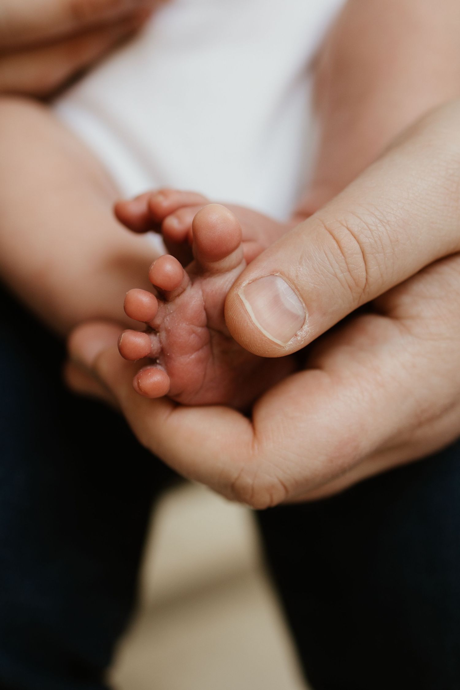 Close-up of a newborn baby's tiny hands resting on a soft beige fleece outfit.