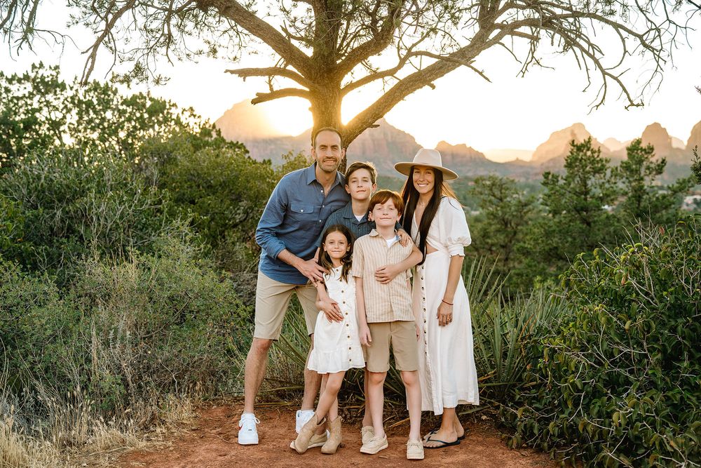 Family of five smiling together at sunset in a desert landscape.