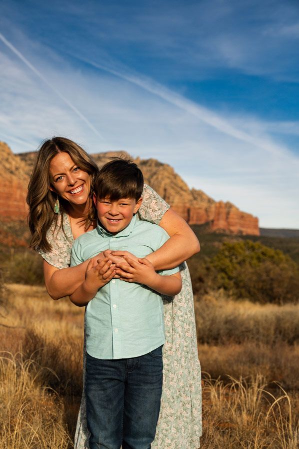 Warm sunset portrait at Sedona red rock mountains with embracing figures against desert landscape.